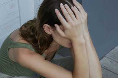 Elleriyle yüzünü kapatan depresif bir kadının portresi.