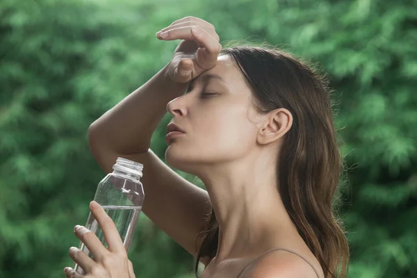 一位年轻女子在炎炎夏日喝瓶装水的户外肖像 水合物的概念 与热浪搏斗的女人 — 图库照片