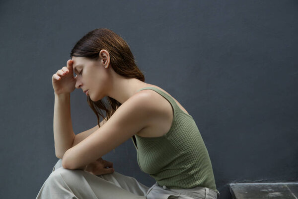 Портрет подавленной женщины, закрывающей лицо руками
