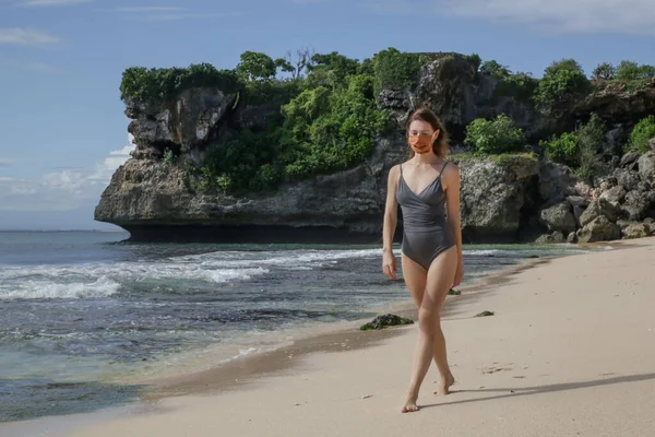 Woman with protective mask on the beach. Summer vacation after Coronavirus pandemic crisis.