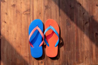 Güneşli bir günde ahşap arka planda renkli terlikler. Tatil tatili. Üst görünüm
