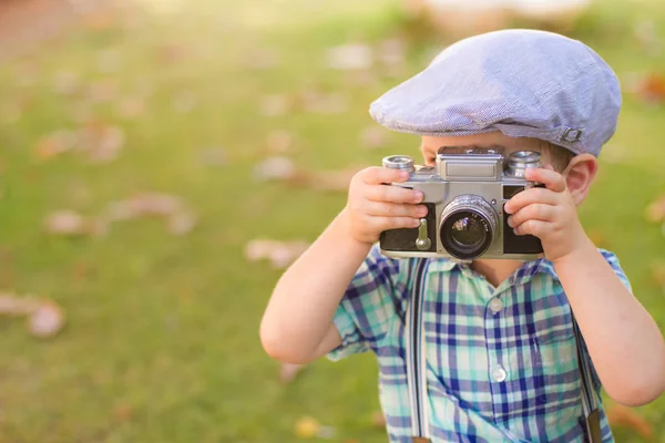 Rapazinho com uma câmara velha a disparar ao ar livre. usando uma câmera de filme retro vintage. campo de verão . — Fotografia de Stock