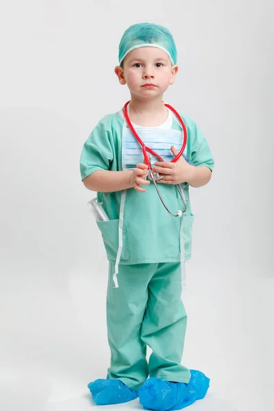 Full längd porträtt av söta leende pojke spelar en läkare. olika yrken. isolerade över vita. Stockbild