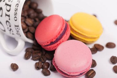Fincan kahve çekirdekleri ile beyaz arka plan üzerinde renkli lezzetli Fransızca macaroons ile yakın çekim