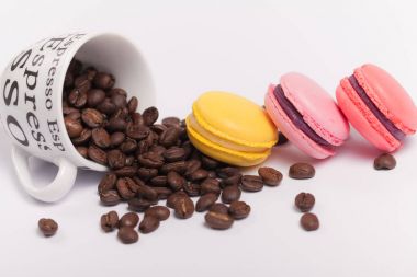 Fincan kahve çekirdekleri ile beyaz arka plan üzerinde renkli lezzetli Fransızca macaroons ile yakın çekim