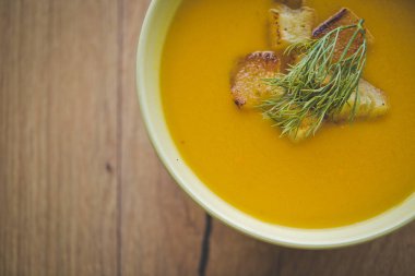 Kraker ve maydanoz ekmek dilimleri ile ahşap arka plan üzerinde kabak ve havuç çorbası