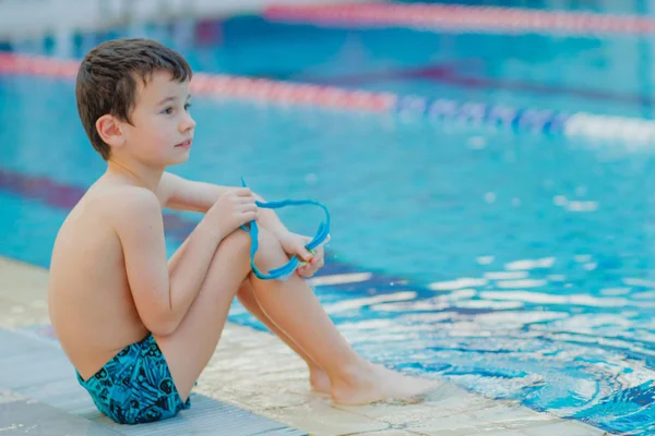 El chico está sentado junto a la piscina — Foto de Stock