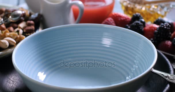 Cereales para el desayuno cayendo en un bol con bayas y frutas secas — Vídeos de Stock