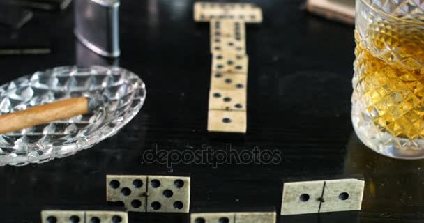 Jugando un juego de dominó con un vaso de whisky y un cigarro — Vídeos de Stock