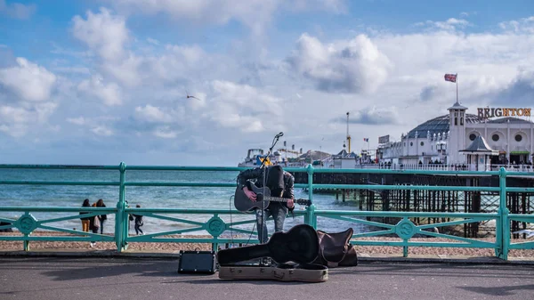 Een straat muzikant met Brighton pier en de zee op de achtergrond — Stockfoto