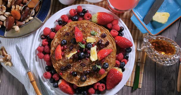 Versare sciroppo d'acero su un pancake con bacche e frutta secca, vista dall'alto verso il basso — Video Stock