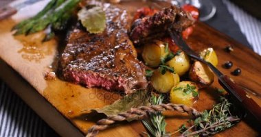 Dolly basarak görünümdeki bir sığır filetosu biftek kuşkonmaz, patates ve közlenmiş domates ile yakından