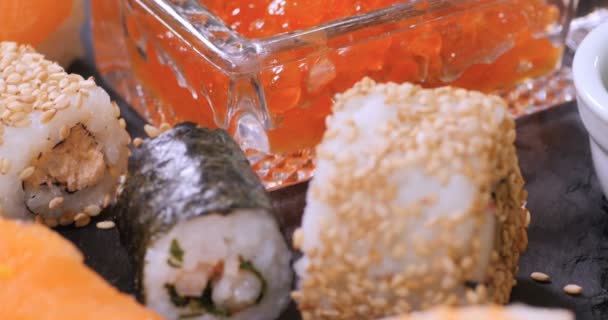 Dolly vista de cerca de un surtido de comida japonesa: sushi, nigiri, sashimi, rollos — Vídeo de stock