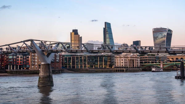 Gente cruzando el puente del Milenio al atardecer con el horizonte de la City de Londres — Foto de Stock
