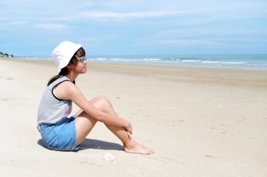 Yaz tatil plaj arka plan üzerinde oturan Asya kız