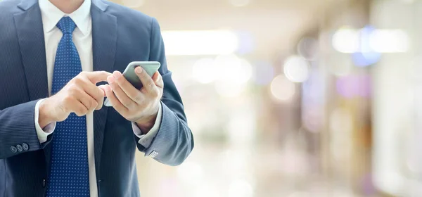 Hombre de negocios manos usando el teléfono inteligente sobre la oficina borrosa con copia — Foto de Stock
