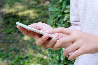 Kadın el akıllı telefon yeşil park arka plan üzerinde kullanma