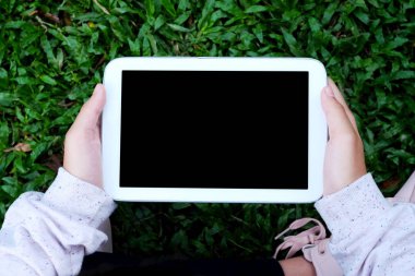 Eli boş ekran tablet yeşil otlar arka plan üzerinde kullanma