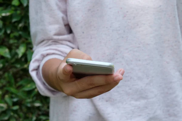 Woman hand using smart phone on green park background — Stock Photo, Image