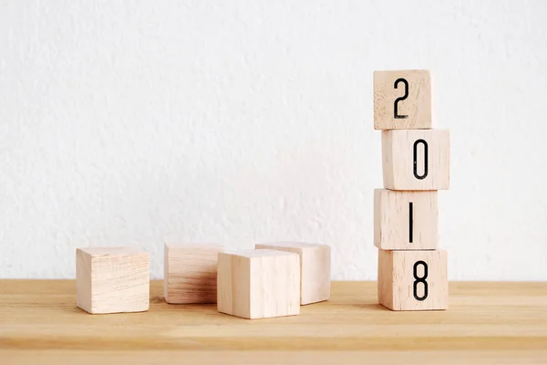 Holzwürfel mit 2018 auf perspektivischem Holz über Tisch und Weiß — Stockfoto