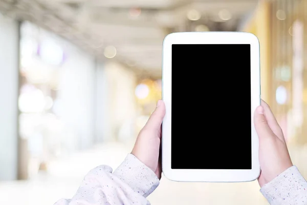 Mano usando la tableta de pantalla en blanco sobre la tienda borrosa con bokeh backgr — Foto de Stock