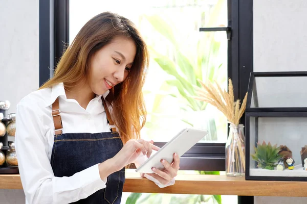 Cafe counter backgrou tablet kullanan genç Asya kadın, barista,