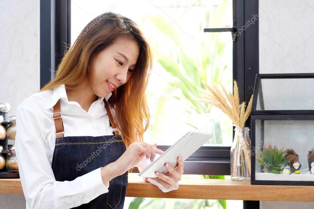 Young asia woman, barista, using tablet at cafe counter backgrou