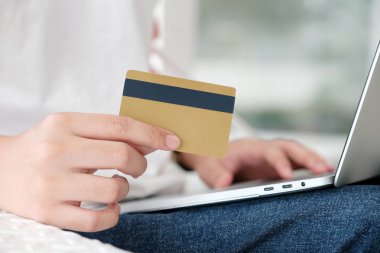 Kredi kartı tutan ve üzerinde alışveriş dizüstü bilgisayar kullanan bir adam