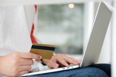 Kredi kartı tutan ve üzerinde alışveriş dizüstü bilgisayar kullanan bir adam