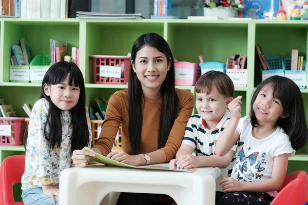 Genç Asyalı kadın öğretmen öğretim çocuklar anaokulu classroo içinde