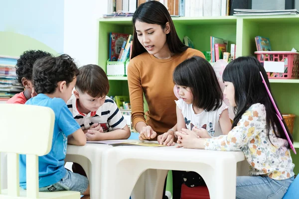 Genç Asyalı kadın öğretmen öğretim çocuklar anaokulu classroo içinde