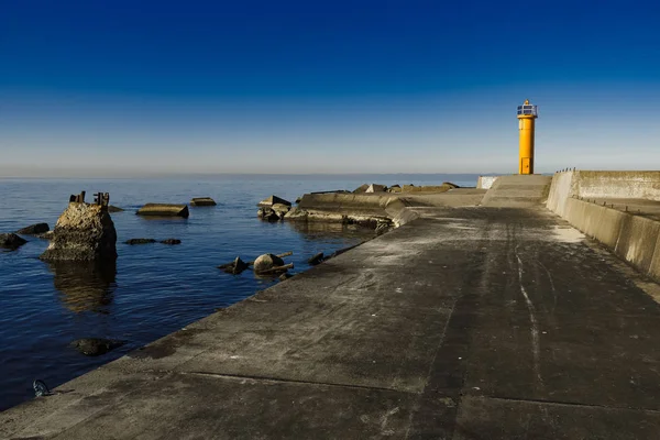 Faro amarillo en dique de rompeolas —  Fotos de Stock