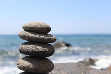 Arka planda kırma dalgalar ile sahilde düzgün taş yığma