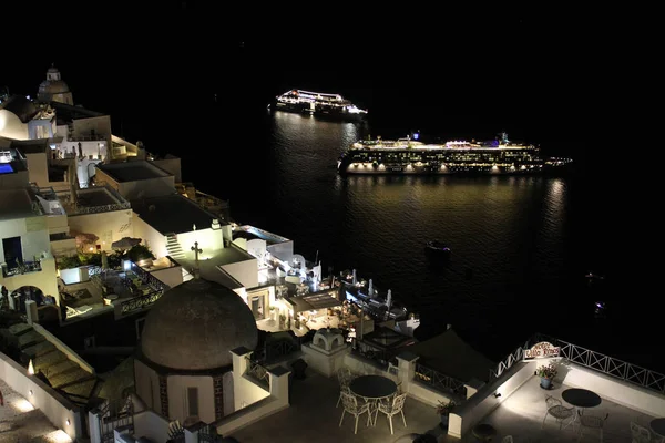 Santornini, Görögország City Skyline éjjel-val tengerjáró hajók az öbölben — Stock Fotó