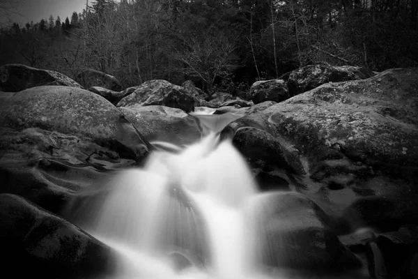 Escala de cinzentos turva movimento e obturador lento Waterscape fotografia de uma queda de água sobre uma grande pedras. — Fotografia de Stock