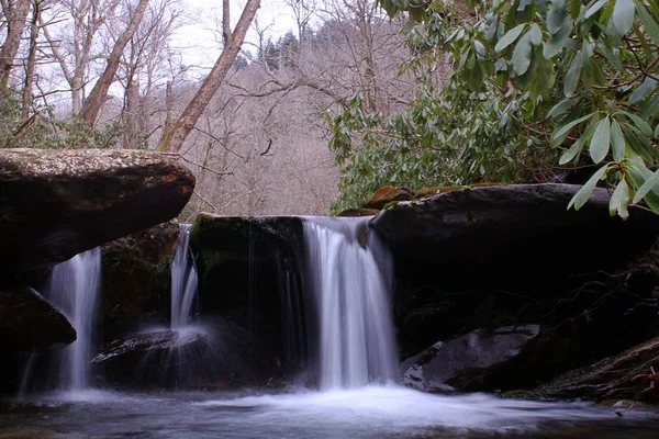 缓慢的快门速度摄影的小河流瀑布与苔藓覆盖的岩石在树林里. — 图库照片