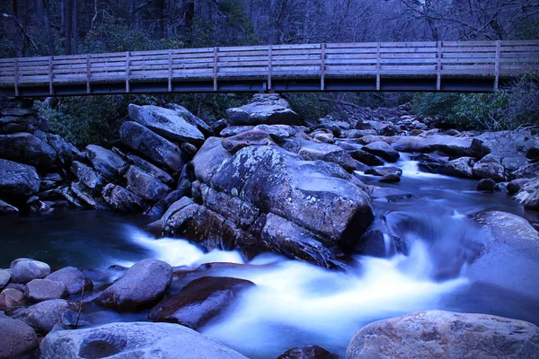 Lassú zársebesség River Photography egy kis vízesés egy fából készült séta út híd a folyón. — Stock Fotó