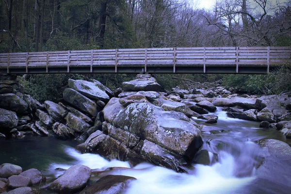 Zeitlupenaufnahmen einer Holzbrücke über einen rauschenden Wasserfall — Stockfoto