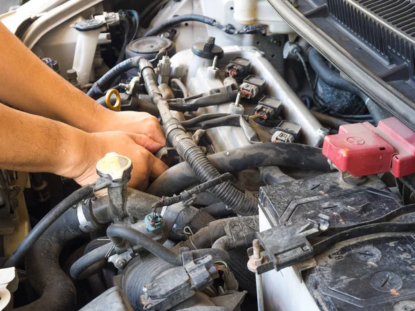 Hand of car mechanic working in auto repair service. He have fix old car engine streaked with dust and oil stains