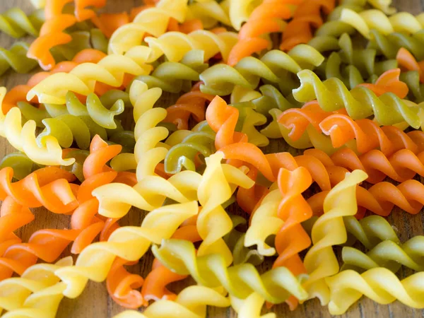 Background of colorful pasta texture close-up. close up of a dried italian pasta on a wooden table.Colored natural pasta — Stock Photo, Image