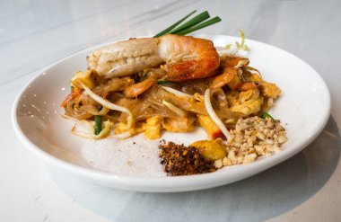 Kızarmış pirinç sopa karides (Pad Tay Goong Sod) ile beyaz bir plaka koymak ve bir beyaz mermer masanın üzerine yerleştirilen