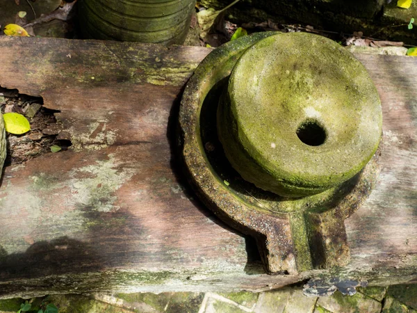 La antigua piedra de molino tiene líquenes verdes alrededor y la antigua piedra de molino colocada en viejas tablas de madera —  Fotos de Stock