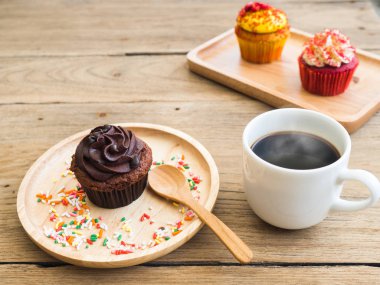 Çikolatalı kek küresel ahşap tabağa koy. Yanında cupcake Vintage çalar saat ve beyaz kahve kupa var