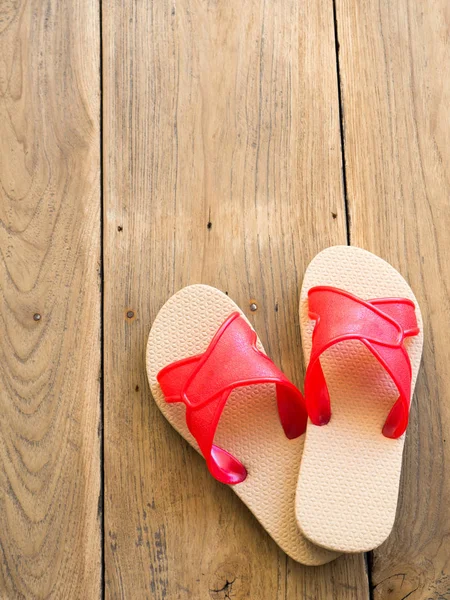 Ahşap zemin üzerinde kırmızı terlik yerleştirilir.