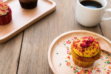 Sarı kek küresel ahşap tabağa koy. Yanında cupca,