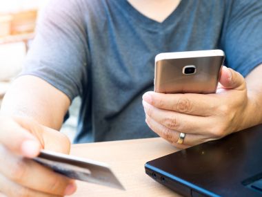 Akıllı kredi kartı tutan ve telefon kullanarak el telefon için alışveriş Online ödeme, ahşap tablo arka bahçede. Online banka kavramı