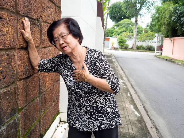 Mujer mayor que tiene dolor en el pecho y su pecho en espera debido a un infarto de corazón. Concepto de ataque cardíaco . — Foto de Stock