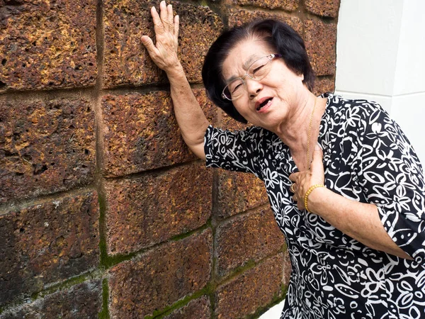 Mujer mayor que tiene dolor en el pecho y su pecho en espera debido a un infarto de corazón. Concepto de ataque cardíaco . — Foto de Stock