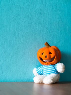Ayı ahşap masaya oturuyor ve Halloween balkabağı şapka tak. mavi ve boşaltmak metin için arka plan olduğunu