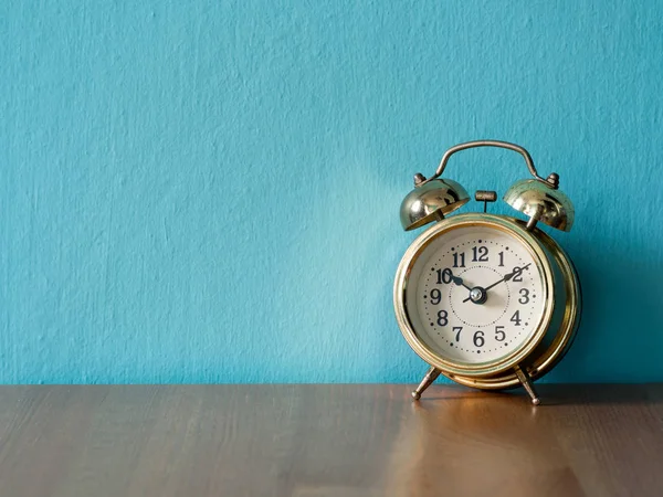Relógio de alarme vintage dourado na mesa de madeira. o fundo é azul e espaço de cópia para texto — Fotografia de Stock
